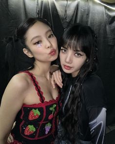 two young women posing for a photo in front of a black backdrop with strawberrys on it