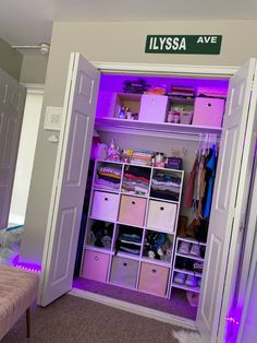 an open closet with purple lights and clothes on the shelves in front of it, next to a bed