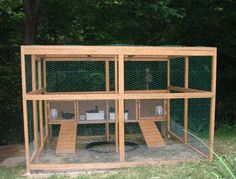 a caged in chicken coop sitting on top of a grass covered field