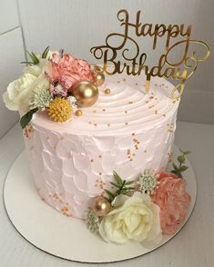 a pink and gold birthday cake with flowers on top