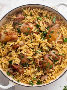 pasta with chicken and parsley in a skillet on a white counter top, ready to be eaten