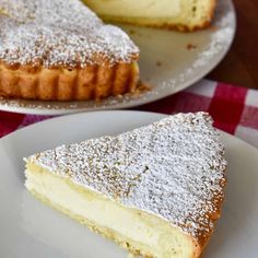 a slice of cheesecake on a white plate with a red and white checkered tablecloth