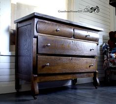 an old wooden dresser sitting in front of a white wall with a teddy bear on it