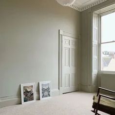 an empty room with two pictures on the wall and a rocking chair in front of it