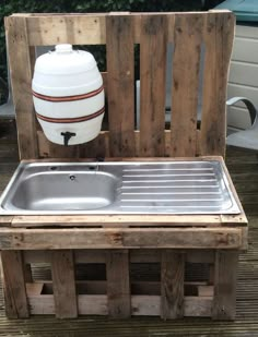 an outdoor sink made out of pallets and wooden crates with a white jug on top