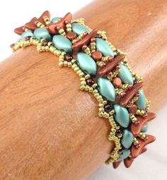 a close up view of a bracelet on a wooden arm with beads and chains attached to it