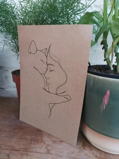 a card with a drawing of a kissing couple on it next to a potted plant