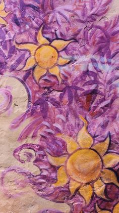 a painting on the side of a building with purple and yellow flowers painted on it