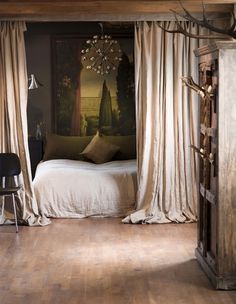 a bed sitting in a bedroom next to a wooden floor covered in white drapes