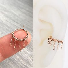 a person is holding two different types of ear piercings on their fingers and the other one has a chain attached to it