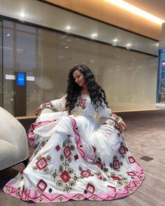 a woman in a white and pink dress sitting on the floor