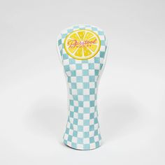 a blue and white checkered vase with an orange slice on the top, sitting in front of a white background