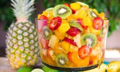 a fruit salad with kiwis, oranges and strawberries in a glass bowl