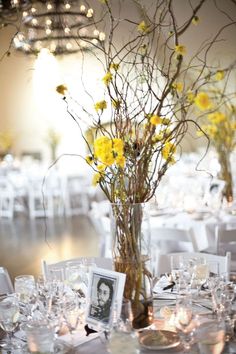 a vase filled with yellow flowers sitting on top of a table covered in white linens