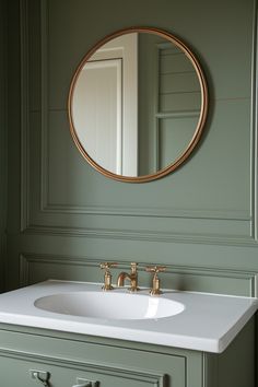 a bathroom sink sitting under a mirror next to a green cabinet with gold faucet