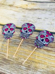 three sugar skull lollipops sitting on top of a wooden table