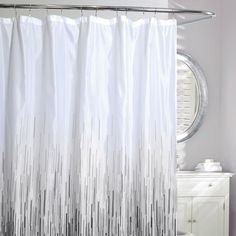 a white shower curtain with black and white stripes on the bottom, in a bathroom