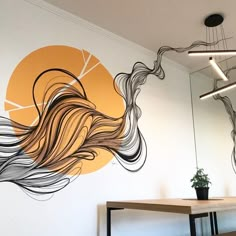 an artistic mural on the side of a wall next to a wooden table and chair