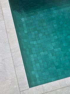 an empty swimming pool with tiled flooring and blue tiles on the side, as seen from above