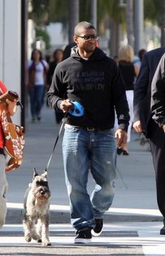 a man walking his dog on a leash down the street with people in the background