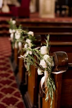 white flowers and greenery line the pews of a church