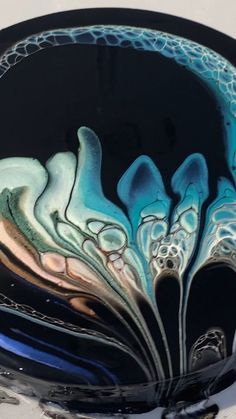 a black and blue glass bowl sitting on top of a table next to a white wall