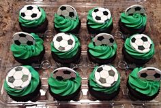 cupcakes with green frosting and soccer balls in a plastic container on a table