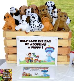 there are many stuffed animals in a crate on the table with a sign that says help save the day by adopting a puppy