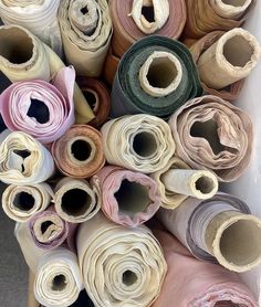 many rolls of different colored fabric are stacked together