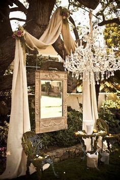 a chandelier hanging from a tree next to a mirror