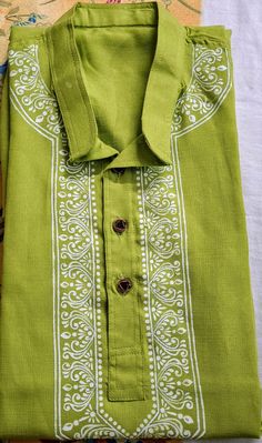 a green shirt with white designs on the collar and cuffs is sitting on a table