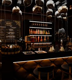 a dimly lit bar with lots of bottles and glasses hanging from the ceiling above it