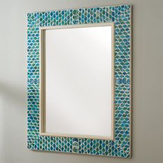 a mirror that is on the wall with a blue and green mosaic pattern around it