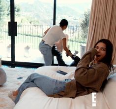 a woman laying on top of a bed next to a man in a white shirt