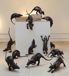 a group of metal rat figurines sitting on top of a wooden floor next to a white box