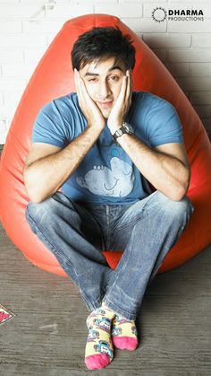 a man sitting on top of a bean bag chair with his hands to his face