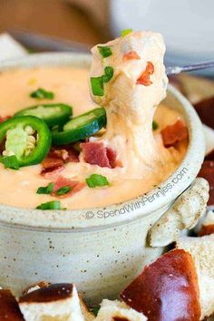 a bowl of soup with green peppers and cheese on top, ready to be eaten