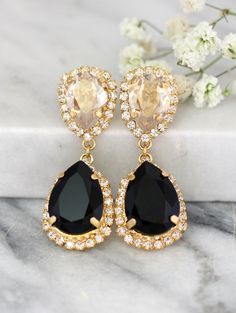 the black tear drop earrings are adorned with gold and crystal stones, along with white flowers