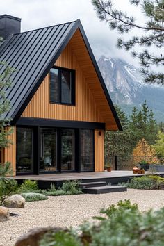 a wooden house with a metal roof and black shingles on the front, surrounded by pine trees