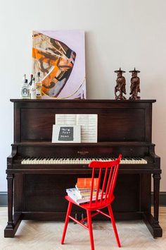 a red chair sitting in front of a piano