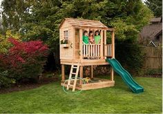 a wooden play house with two children on it and a slide in the back yard