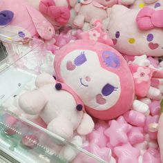 there are many stuffed animals on display in the store together and one is pink with purple eyes