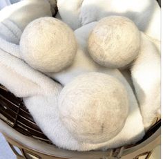 three balls of white wool sit in a basket on the floor next to a towel