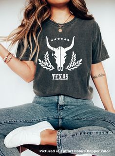 Texas cow skull tee shirt. This short sleeve crew neck tee is the perfect t for anyone who loves the State of Texas.  The eye-catching graphic and Texas style grunge font western vibe and make the shirt a great gift for anyone who visits or lives in Texas.  The tee is a quality tee shirt known for its comfortable fit and feel. Comfort Colors is a garment-dyed t-shirt tee made 100% with ring-spun cotton. The soft-washed, garment-dyed fabric brings extra coziness to your wardrobe while the relaxed fit makes it an excellent daily choice. The double-needle stitching throughout the tee makes it highly durable while the lack of side-seams helps the shirt retain its tubular shape. .: 100% ring-spun cotton .: Medium fabric (6.1 oz/yd² (206.8 g/m .: Relaxed fit .: Sewn-in twill label Skull Tee Shirt, Texas Western, Skull Tee, Texas Style, Bull Skulls, Cow Skull, Crew Neck Tee, Dye T Shirt, Comfort Colors