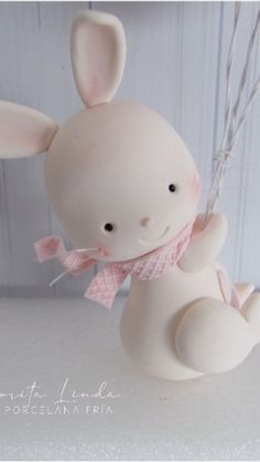 a white rabbit figurine hanging from a string with pink ribbon around it's neck