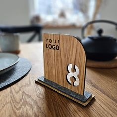 a wooden business card holder sitting on top of a table next to a teapot