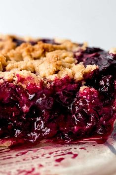 a close up of a pie on a plate with blueberry sauce and crumbs