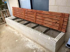 a bench made out of wooden slats sitting on the side of a building next to a window