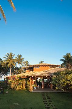 a house that is surrounded by palm trees and green grass with steps leading up to the front door