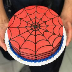 a spider - man cake on a plate being held by a person's hands